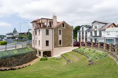a house on a hill next to a stone wall at Apartamento con jardín en San Sadurniño in Santa María La Mayor del Rosario