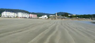 an empty beach with buildings in the background at Alojamientos Viveiro - Playa de Covas II in Viveiro