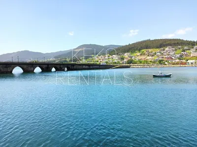 a boat in the water next to a bridge at Casa Lolita 1 in Viveiro