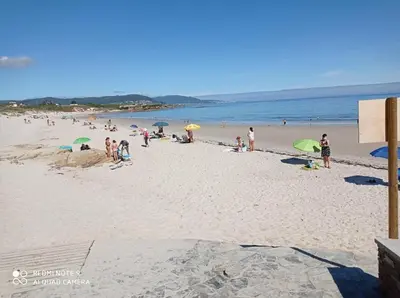 a group of people on a beach with umbrellas at EnFOZ PLAYA DE LLAS in Foz