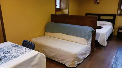 a room with two beds and a chair in it at OSO4 in Pola de Somiedo