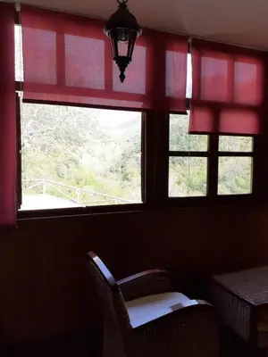 a window with red curtains and a chair in a room at CASA OSO 1 in Pola de Somiedo
