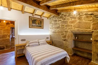 a bedroom with a bed and a stone wall at Casapepe in Nogueira de Ramuin