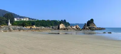 a sandy beach with a house in the distance at Mariña in Viveiro