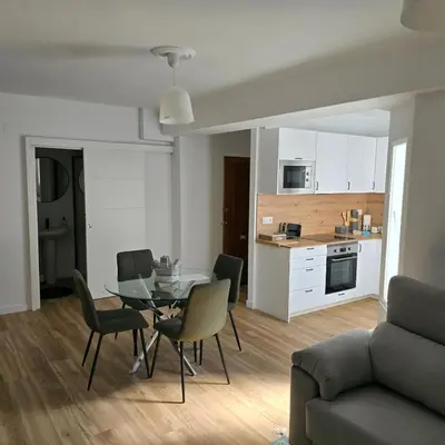 a living room with a table and chairs and a kitchen at piso libertad in Ourense