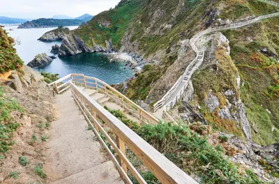 a staircase leading up a mountain next to a body of water at EnVIVEIRO Destino Playa de Covas in Viveiro