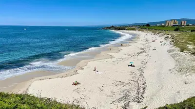a group of people on a beach next to the ocean at The Cliffs A Ribeira - Pampillosa in Foz