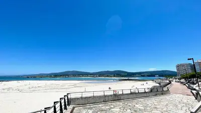a beach with a fence and people on the sand at The Cliffs A Ribeira - Rapadoira in Foz
