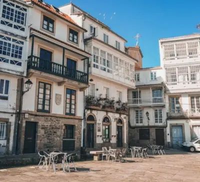 a group of buildings with tables and chairs in front of them at Adiva Suite in Puentedeume