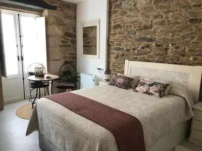 a bedroom with a bed and a stone wall at Estudios rúa Maior, 49-2B in Sarria