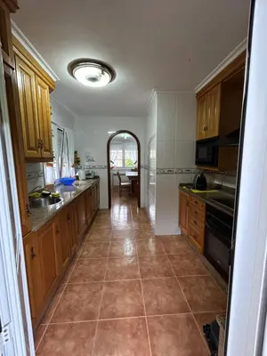 a kitchen with wooden cabinets and a tile floor at Preciosa casa en A Caridad in La Caridad