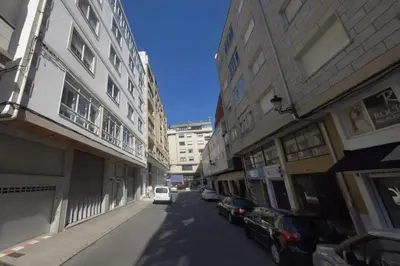 a white car driving down a street next to buildings at XELIÑA c in A Estrada