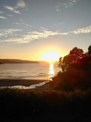 a sunset over the water with the sun setting at The Cliffs - AT Seiramar Area in Viveiro