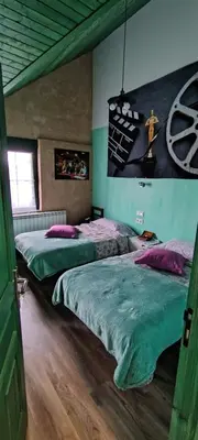 a bedroom with two beds and a painting on the wall at Alberguecasaflor in Murias de Rechivaldo