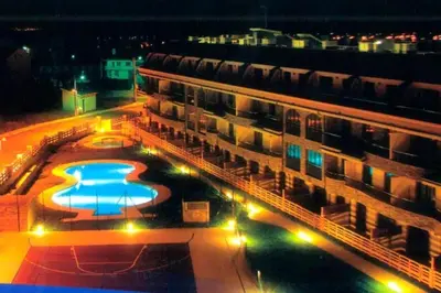 a building with a swimming pool next to a building with lights at Apartamento Herosa 2 Spa in San Miguel de Reinante