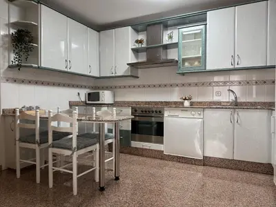 a kitchen with white cabinets and a table with chairs at BierzINN Alojamientos - Martina in Ponferrada