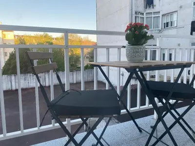 a table and chair on a balcony with a vase of flowers at La Huella de Caldas in Caldas de Reis