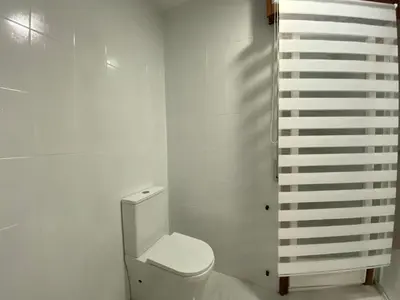 a bathroom with a toilet and a white wall at A tres Pasos in Caldas de Reis