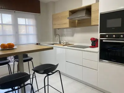 a kitchen with white cabinets and a counter with stools at A tres Pasos in Caldas de Reis