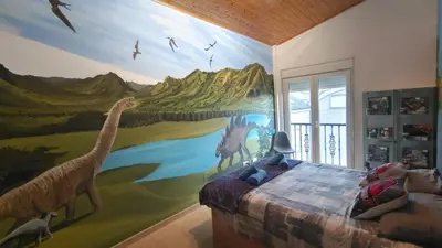 a bedroom with a mural of dinosaurs on the wall at Nuestro sueño jurásico in Barreiros