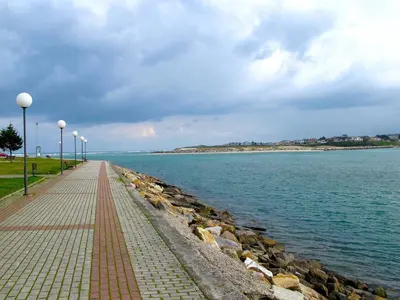a brick walkway next to the water with a rock wall at EnFOZ 1ª Línea de Playa II in Foz