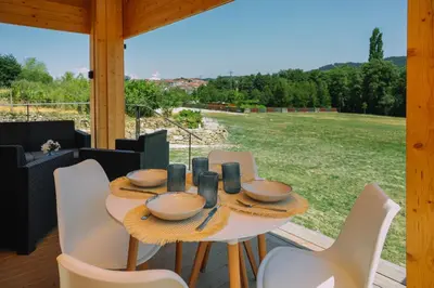 a table and chairs on a porch with a view of a field at Cabañas de Allariz in Allariz