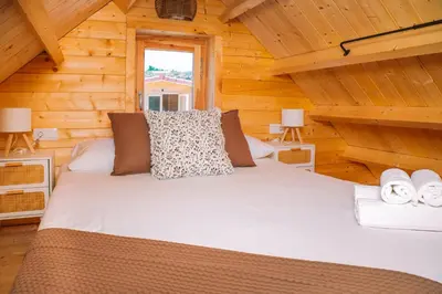 a bed in a log cabin with two lamps at Cabañas de Allariz - Cabaña 3 in Allariz