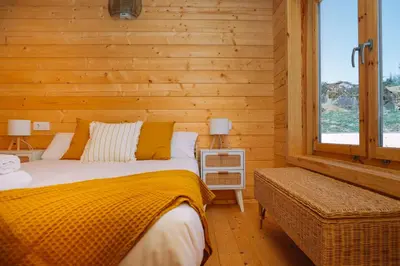 a bed in a room with a wooden wall at Cabañas de Allariz - Cabaña 4 in Allariz