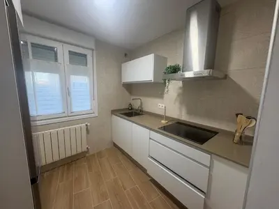 a small kitchen with white cabinets and a sink at El pisito de Cris y Mia in Ponferrada