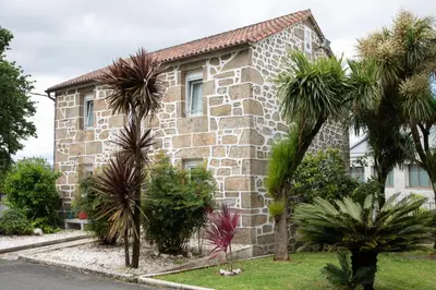 a stone house with palm trees in front of it at Charming house in Teo with balcony and parking included in Rua De Francos