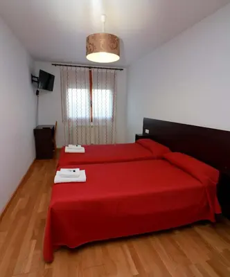 a bedroom with a red bed with a red blanket at APARTAMENTOS CASAS NOVAS in Silleda
