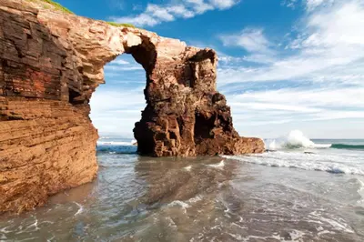 an arch in a rock formation in the ocean at Stone Cottage FISTERRA in Curtis