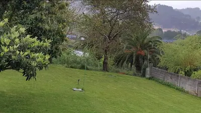 a grassy field with a fence and trees and a river at CHALT EN MIÑO CON VISTAS AL MAR in A Coruña