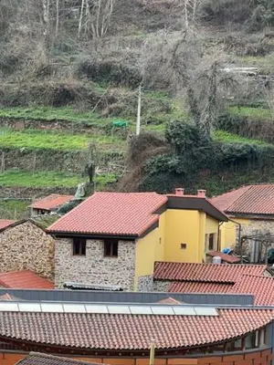 a group of buildings with red roofs on a mountain at La Puchera in Cangas del Narcea