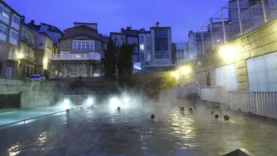 a group of people swimming in a fountain at night at Polvorín in Ourense