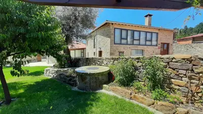 a stone house with a stone wall and a stone bench at O Fogón - Casa Ferrador (Ribeira Sacra) in Sober