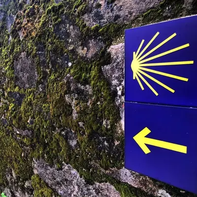 a blue sign with an arrow on a stone wall at Apartamento Padron Centro P8 by URent in Padrón