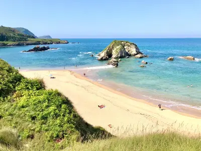 a beach with people swimming in the ocean at The Cliffs - Sunset Village Beach 1C in Viveiro