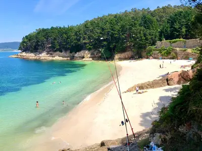 a beach with a group of people in the water at The Cliffs - Sunset Village Beach 1C in Viveiro