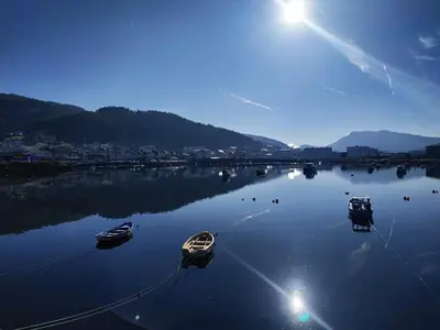 three boats are docked in a large body of water at The Cliffs - Sunset Village Beach 3C in Viveiro