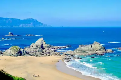 people on a beach with rocks in the ocean at The Cliffs - Sunset Village Beach 3C in Viveiro
