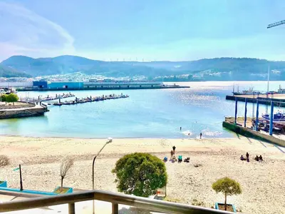 a beach with people in the water and a pier at The Cliffs - Sunset Village Beach 3C in Viveiro
