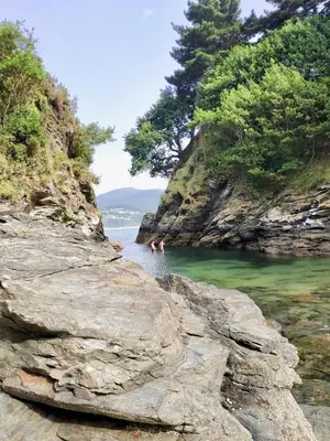 two people swimming in a body of water at The Cliffs - Sunset Village Beach 3E in Viveiro
