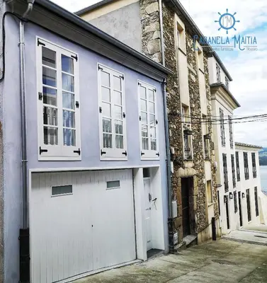 a building with a white garage door and windows at Cabanela Maitia Apto Matteo Barbacoa in Ribadeo