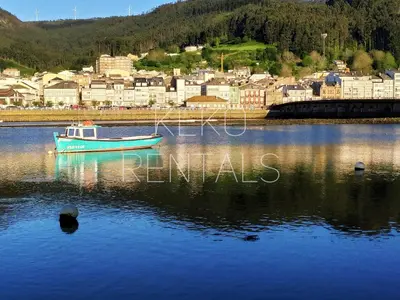 a boat in the water with a town in the background at Camiño Vello in Viveiro