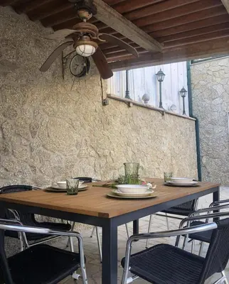 a wooden table with chairs and a ceiling fan at A casiña de Estela in Caldas de Reis
