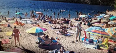 a crowd of people on a beach with umbrellas at Casa jardin Mariana in Lubián