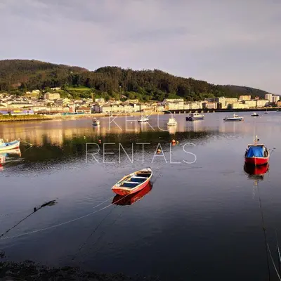 three boats are docked in a body of water at La Casa de Ana in Viveiro