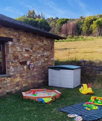 a backyard with a sandbox and toys in the grass at O Busto Aldea Rural, Apartamento HORNO 1 in Puebla del Brollón