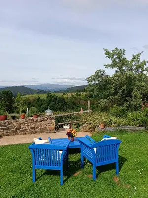 two blue benches sitting next to a table in the grass at Apartamento Felicitas en La Casa de Cobos, Ribeira Sacra in Puebla del Brollón